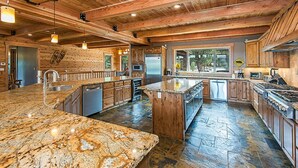 A spacious kitchen with granite countertops, wooden cabinets, and a large island.