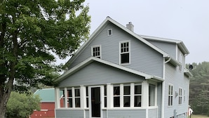 Ein zweistöckiges Haus mit Veranda und einem Schild, das es als Gästehaus kennzeichnet.
