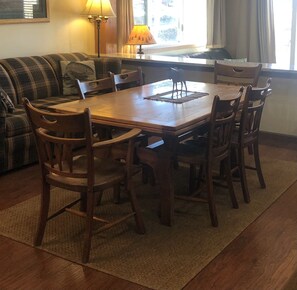 Un comedor con una mesa y sillas de madera, un sofá y una lámpara.