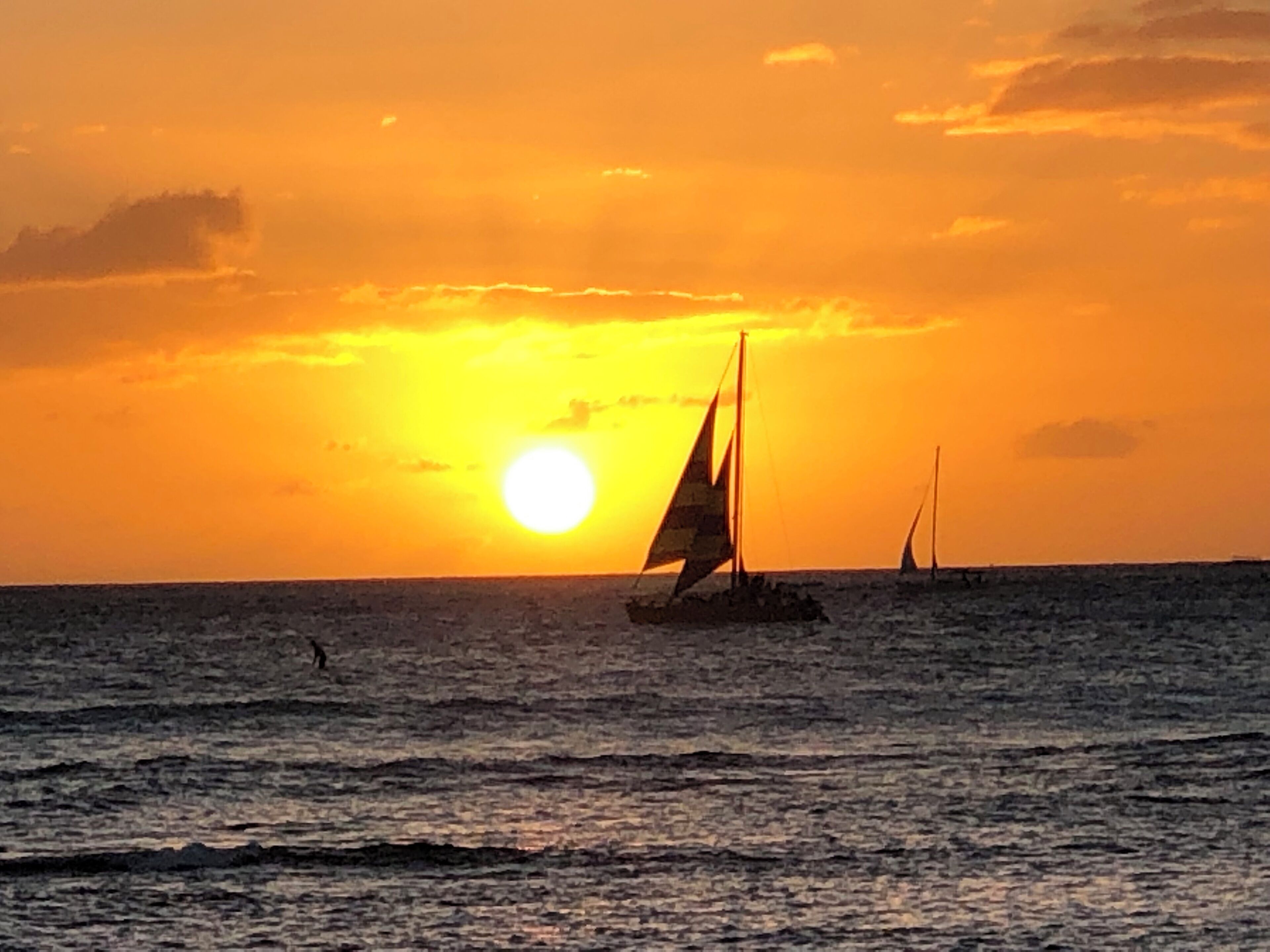 Ein Sonnenuntergang über dem Meer mit Segelbooten.