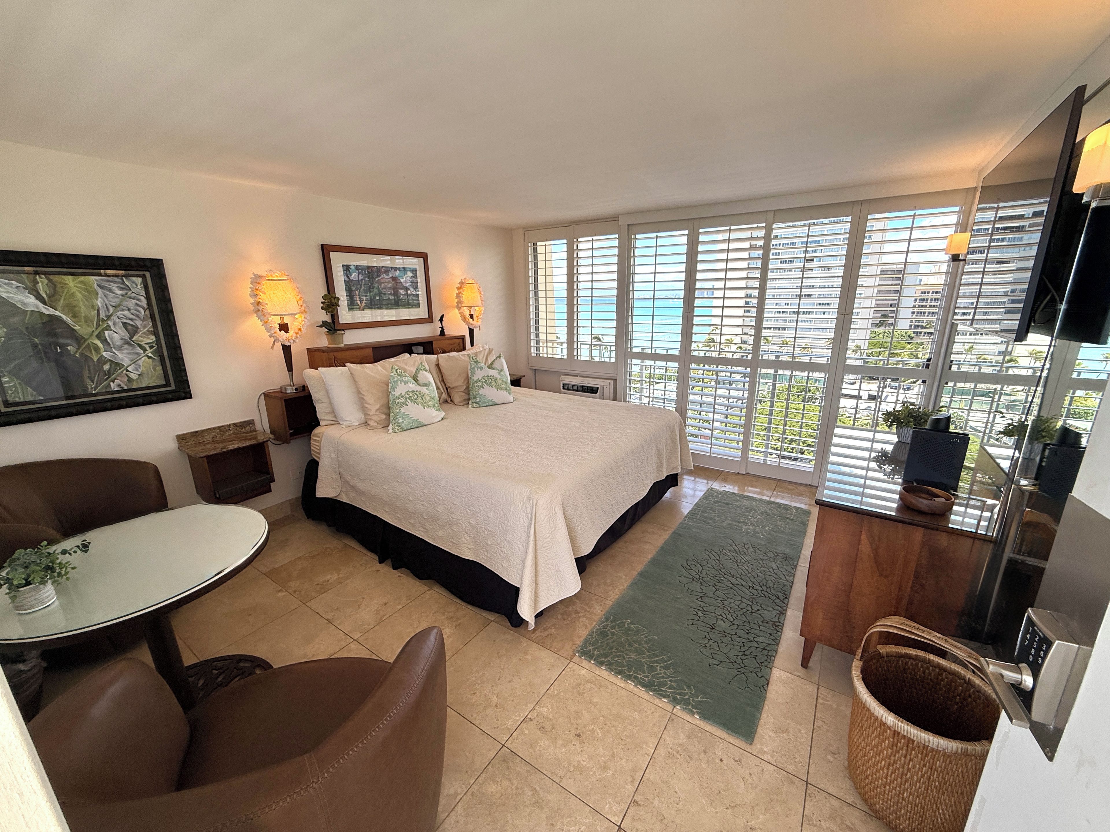 Una habitación de hotel con cama, escritorio, silla, ventana con vistas y televisión.