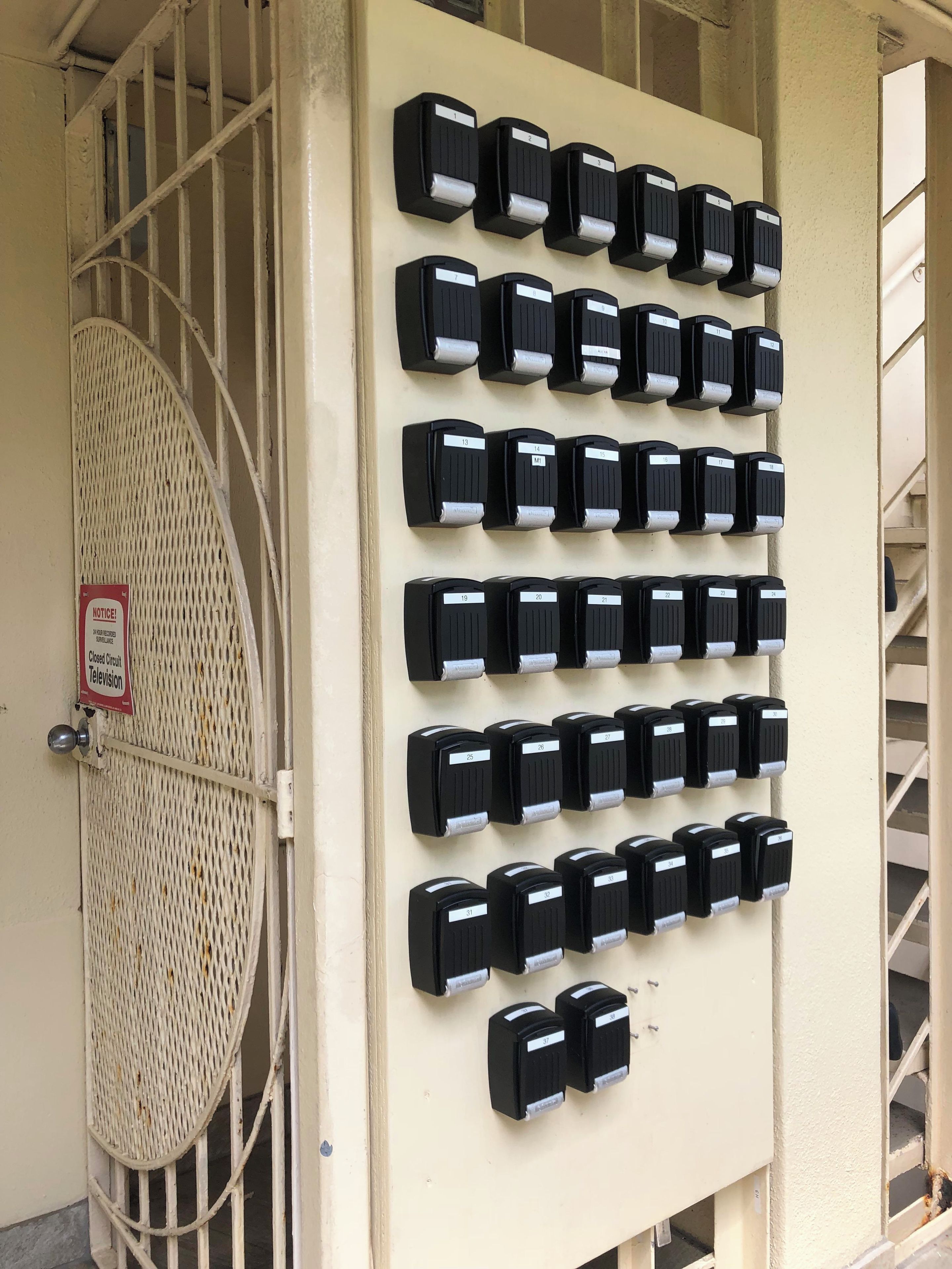 A wall-mounted panel with numbered call buttons, a notice sign, and a barred entrance.