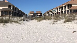 Ein Strandhotel mit einem Sandweg, der zum Gebäude führt.