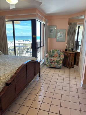 Une chambre avec un grand lit, une chaise, une petite table et une vue sur la plage.
