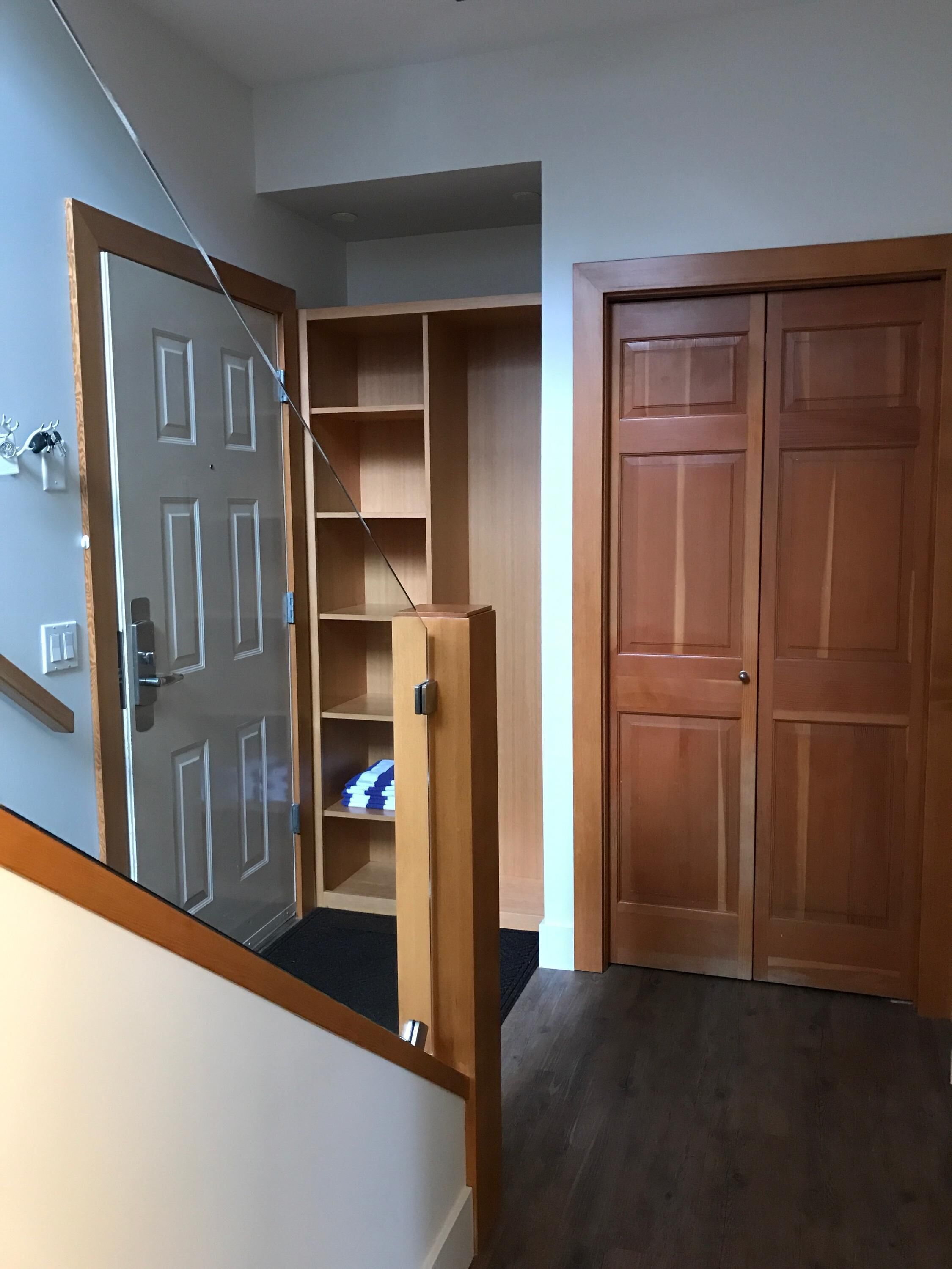 Ein Flur mit einer Holztür, einer Glastür und einem Holzschrank.
