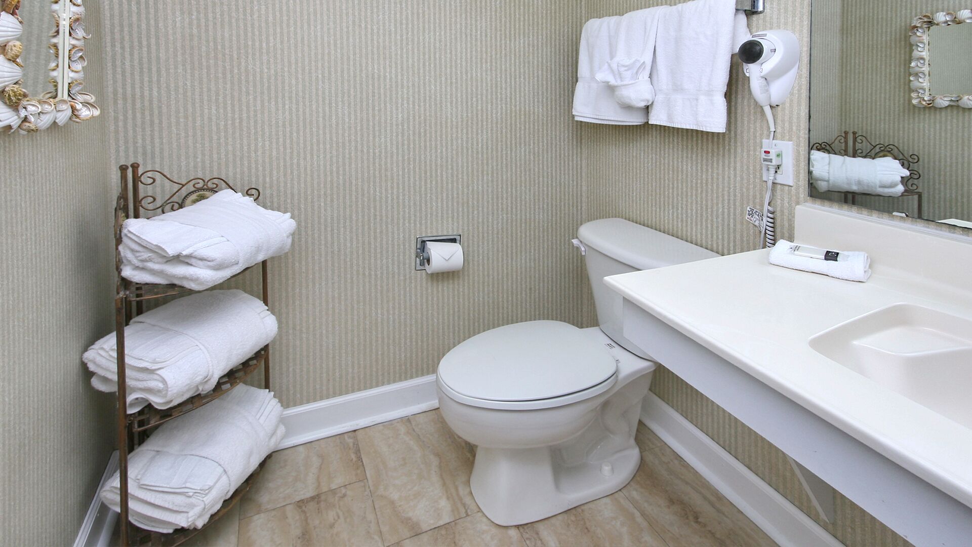 A bathroom with a toilet, a towel rack, a hand dryer, and a sink.