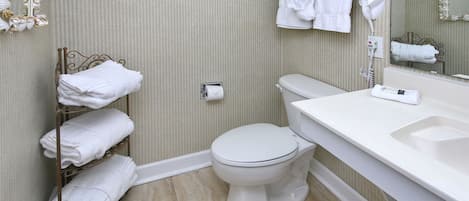 A bathroom with a toilet, a towel rack, a hand dryer, and a sink.