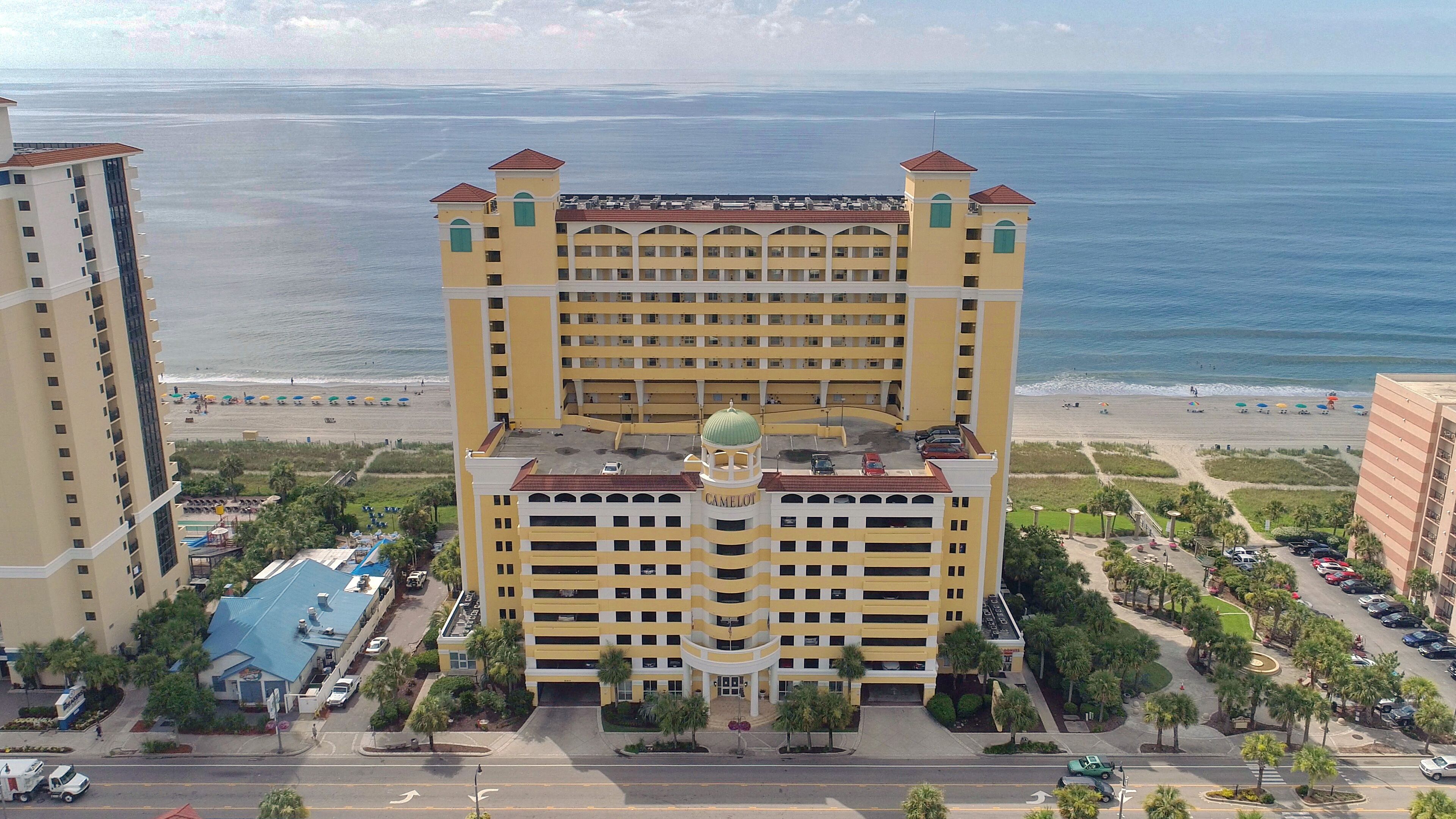 Ein Hochhaus-Hotel mit Innenhof, mehreren Balkonen und Blick auf den Strand.