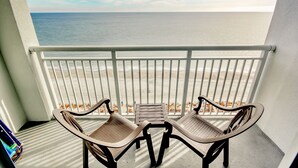 Un balcon avec deux chaises et une petite table, donnant sur une plage.
