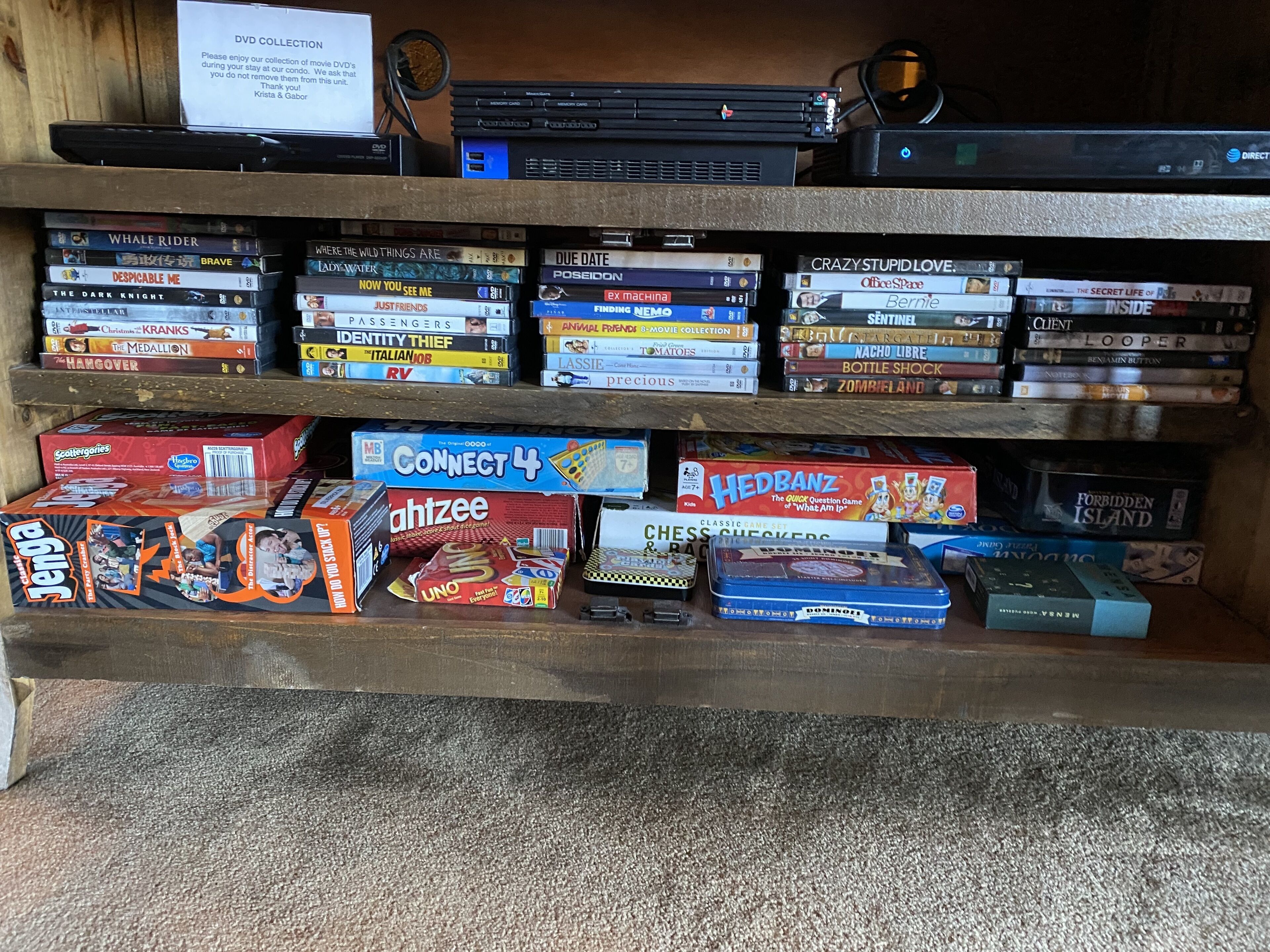 Una estantería con varios DVD, juegos de mesa y un cartel que indica 'Colección de DVD'.