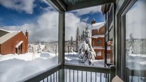 Paisaje nevado con un edificio de madera y una vista por una ventana.