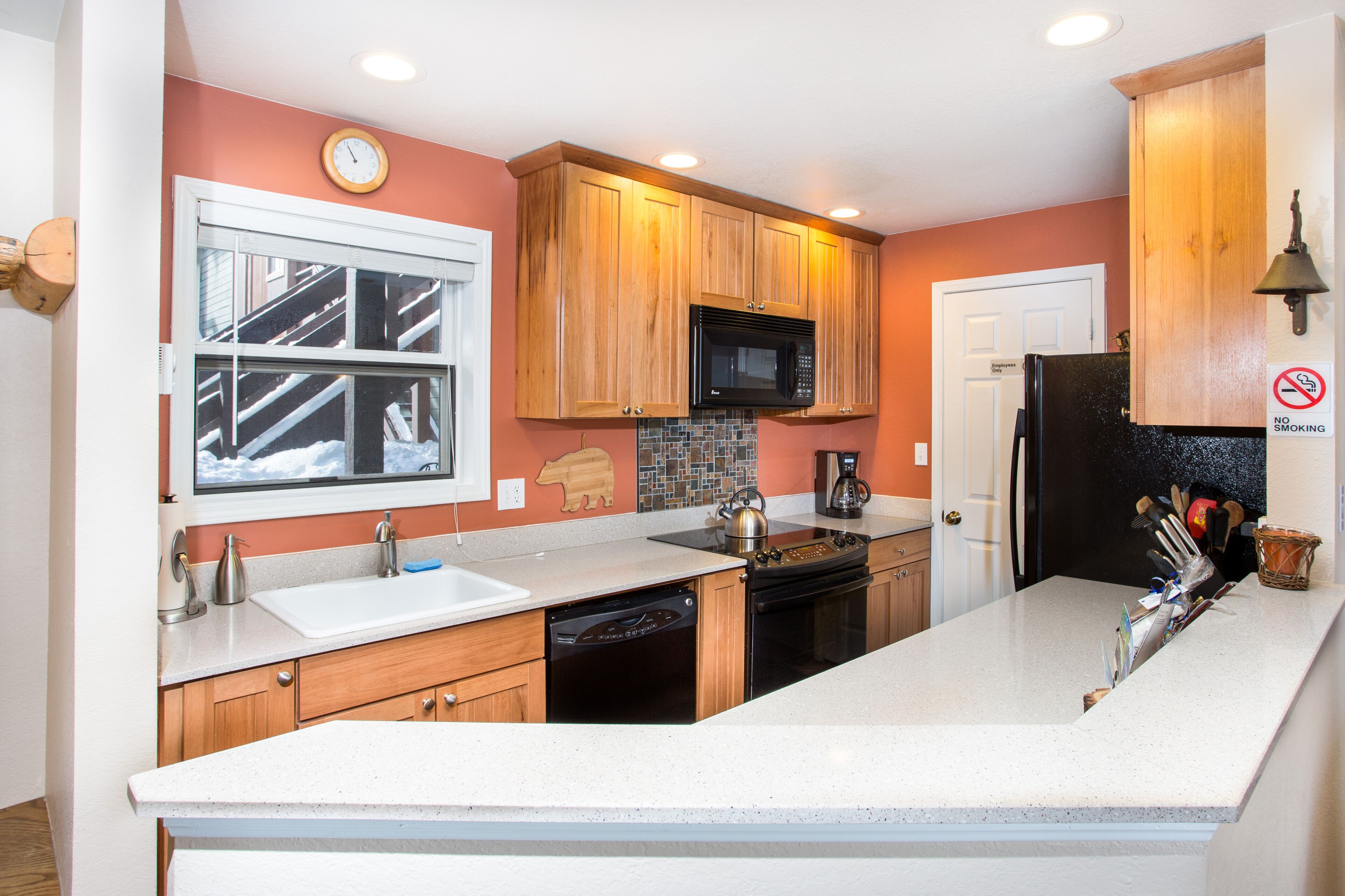 A kitchen with wooden cabinets, a microwave, a stove, and a sink.