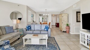 A living room with a grey sofa, a white coffee table, and a blue patterned rug.