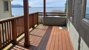 Una terraza de madera con vistas al mar y a las montañas.