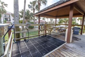 A wooden deck with a metal grate, a covered seating area, and a trash bin labeled for aluminum cans only. - Ocean Village Club R17 Exceptionally Clean! On the Beach! OVER 280 "5 STARS" (St. Augustine)