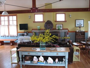 A cozy living room with a wooden bench, a fireplace, and a vase of yellow flowers. - Walk to Private Beach, Great screened porch, Chefs kitchen, Open beam design (Union Pier)