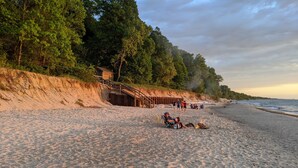 A sandy beach with a wooden staircase leading up to a building, surrounded by trees. - Walk to Private Beach, Great screened porch, Chefs kitchen, Open beam design (Union Pier)