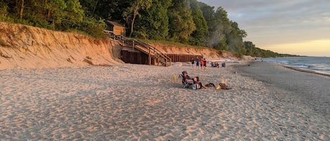 A sandy beach with a wooden staircase leading up to a building, surrounded by trees.