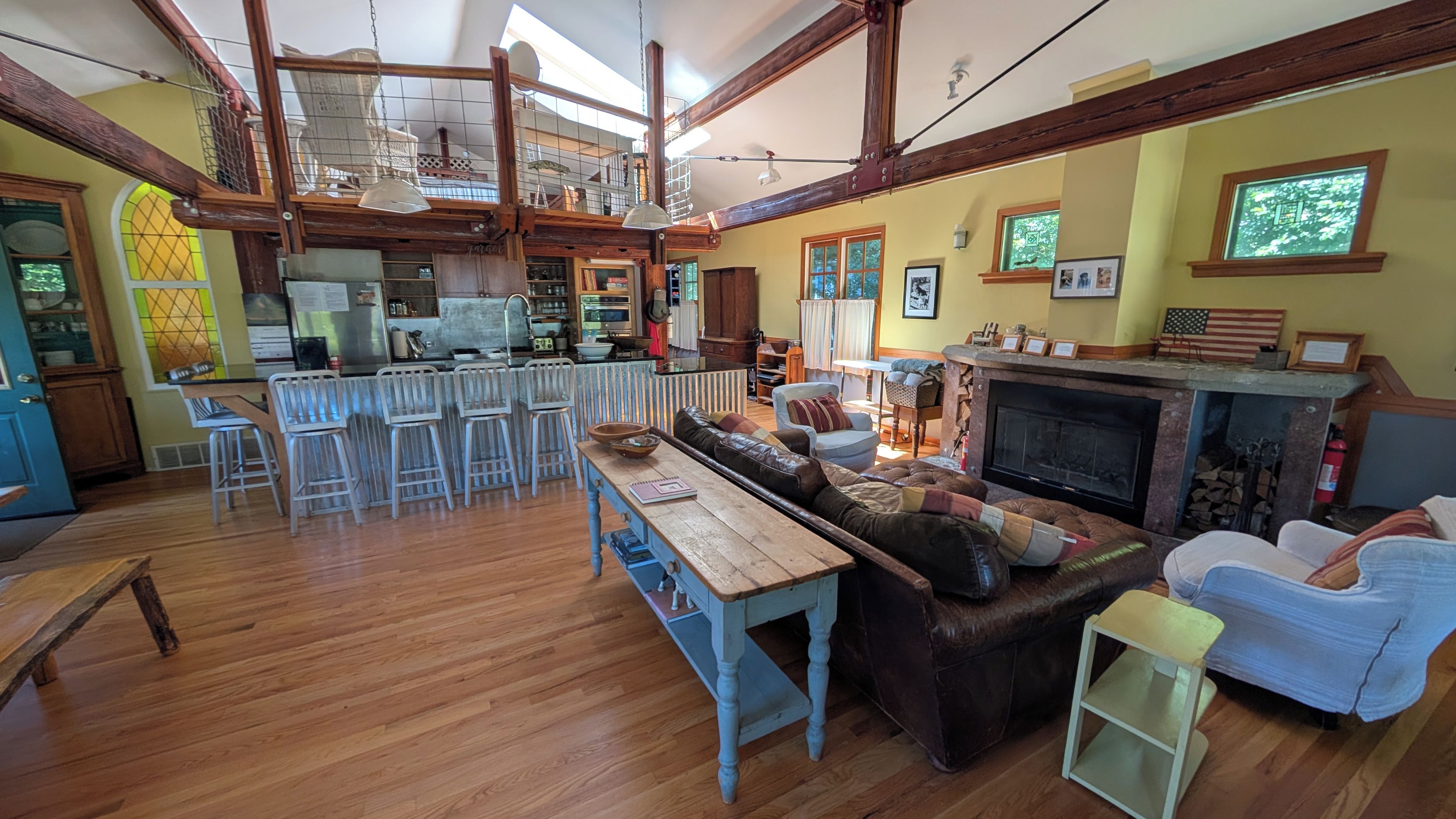 A spacious living area with a fireplace, a dining table, and a kitchen in the background.