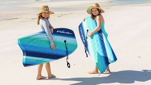 Deux personnes sur une plage, tenant des planches de surf.