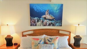 A hotel room with a bed, two bedside tables with lamps, a clock, and a painting of a sea turtle on the wall. - Ocean Front Napili Point C20 Amazing View  A/C  Freshly Remodeled for 2025! (Napili, Lahaina)
