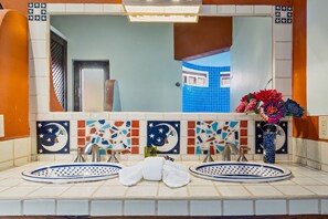 Un baño con dos lavamanos, un espejo y un elegante revestimiento de azulejos.
