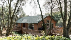 Eine Hütte mit einer Terrasse, umgeben von Bäumen.