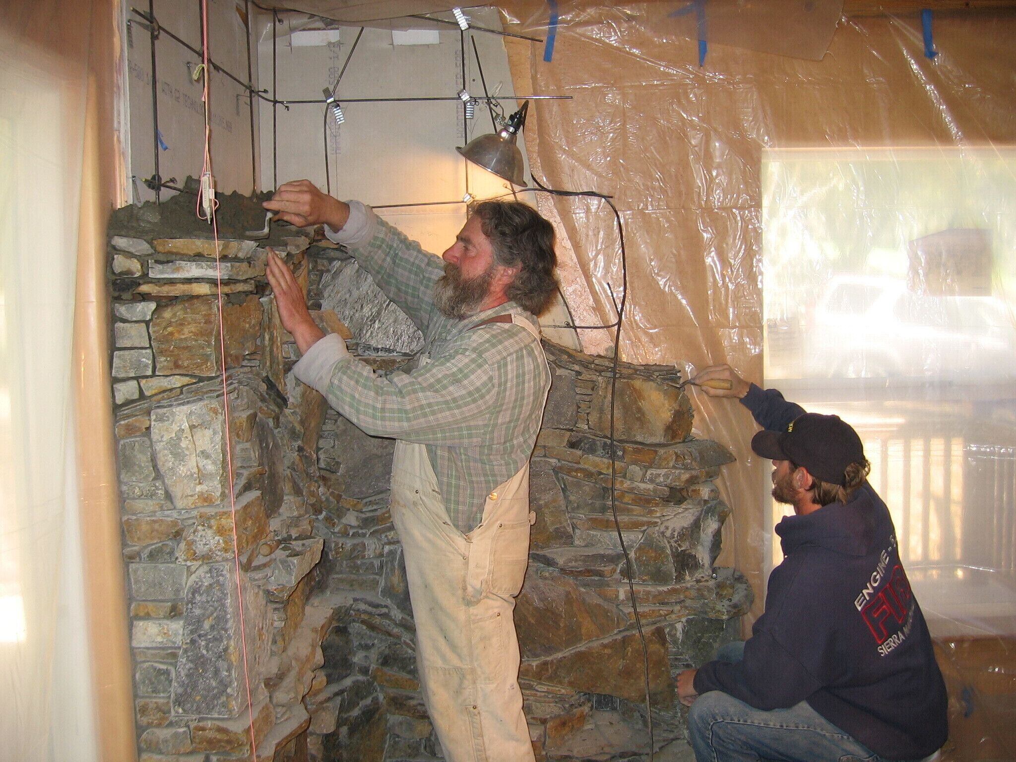 A person working on a stone wall, possibly in a construction or renovation setting.