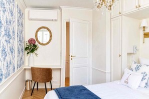 A hotel room with a bed, a desk, a chair, a wardrobe, and a mirror. - Spacious, Enchanting 1 Bedroom + Balcony and Insta-worthy Eiffel View (Paris)