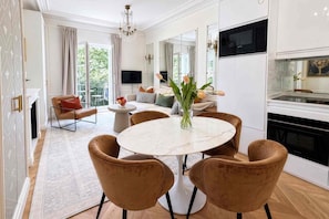 A modern dining area with a marble table, velvet chairs, and a vase of flowers. - Spacious, Enchanting 1 Bedroom + Balcony and Insta-worthy Eiffel View (Paris)