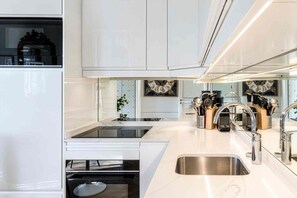 A modern kitchen with white cabinetry, a stainless steel sink, and a variety of kitchen utensils. - Spacious, Enchanting 1 Bedroom + Balcony and Insta-worthy Eiffel View (Paris)