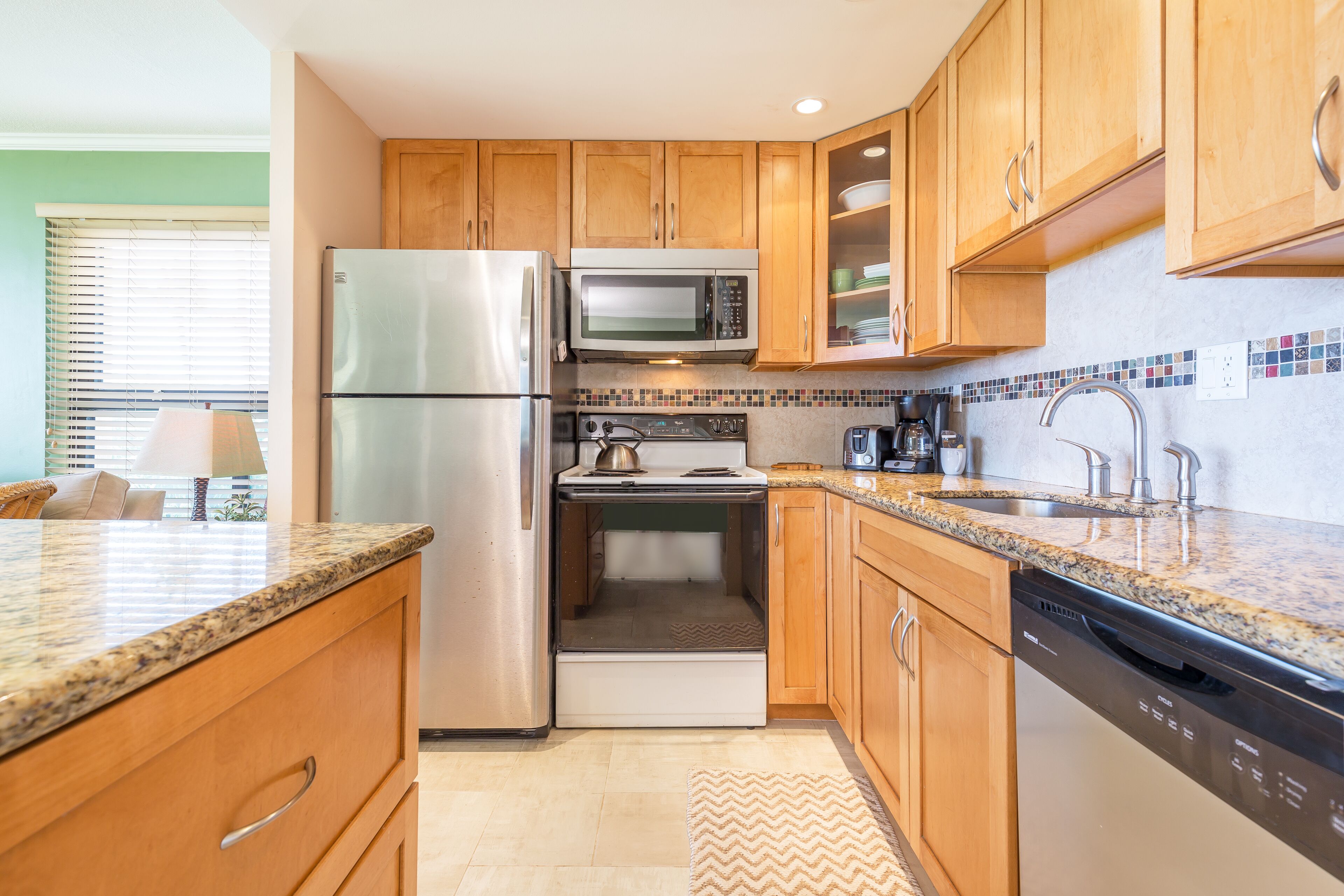 A modern kitchen with wooden cabinets, stainless steel appliances, and a tiled backsplash.