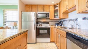 A modern kitchen with wooden cabinets, stainless steel appliances, and a tiled backsplash.