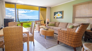 A living room with wicker furniture, a sofa, a coffee table, and a view of the ocean. -  Beachfront ,Ground floor, Sugar Beach, Corner  unit 114 - Steps to the Ocean!!! (Kihei)