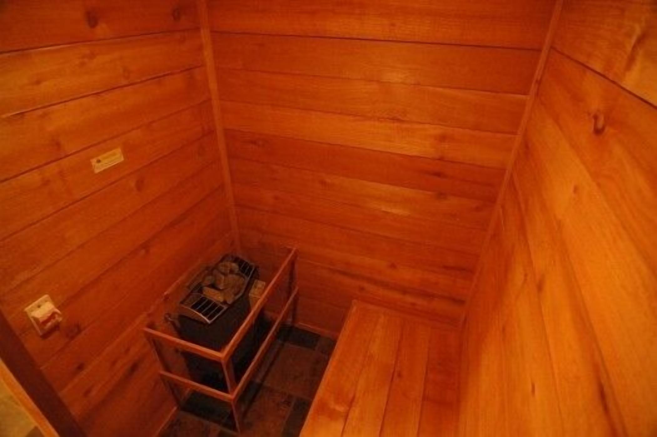 A small, wooden cabin with a bench and a metal rack holding items.