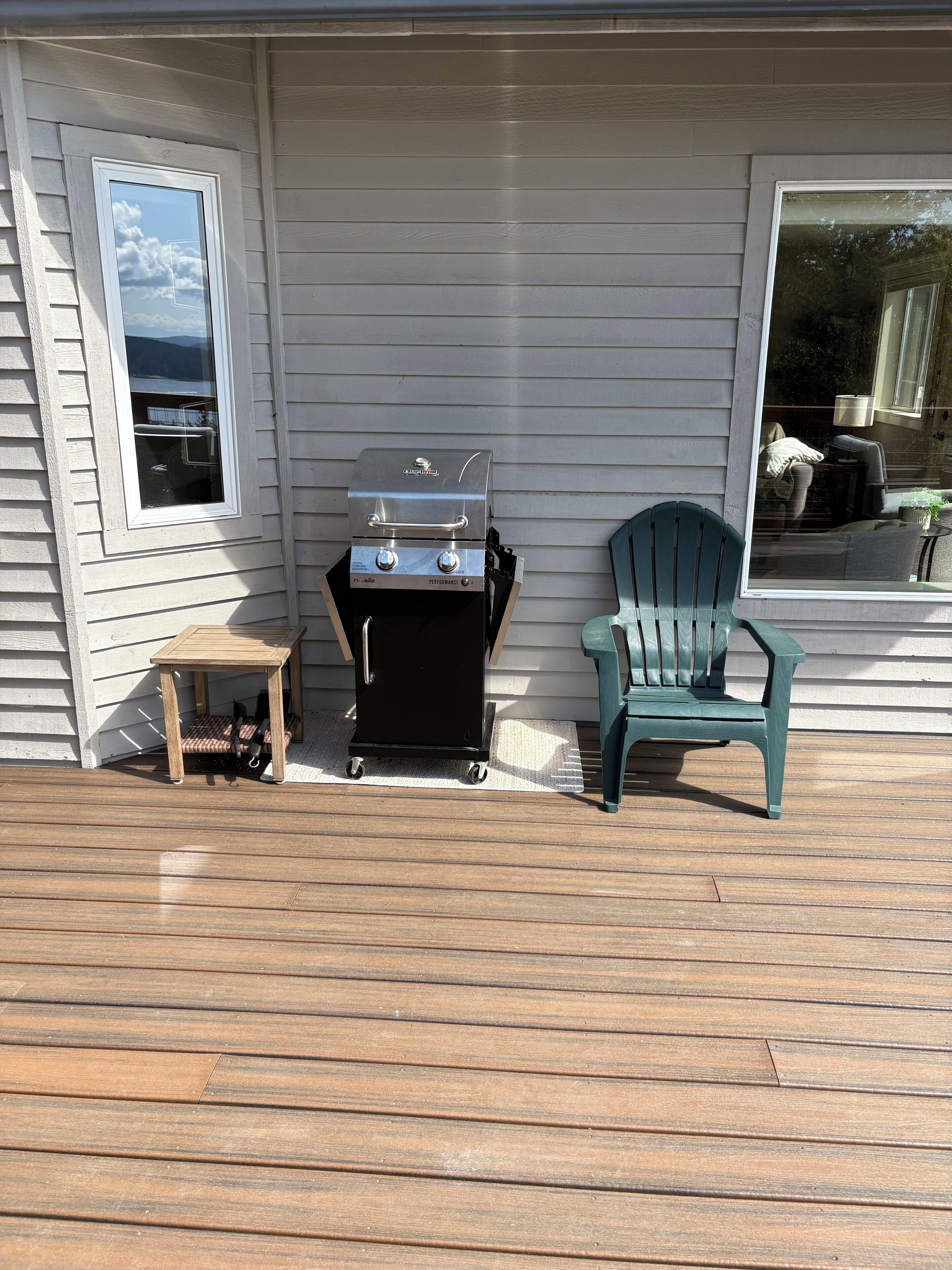 A deck with a grill, a chair, and a small table.