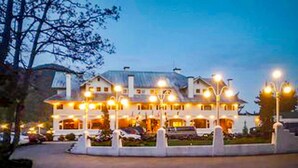 A large, multi-story hotel with a well-lit entrance and a driveway leading to parked cars. - Orcas-Beautiful Modern Home- Large New Deck- Water View- Privacy- Dog Friendly (Rosario)