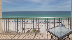 A balcony with a view of a beach, a table, and umbrellas. - AVAILABLE:4/12-4/19/895 /7 night/Couples Retreat/ balcony over looking beach (Panama City Beach)