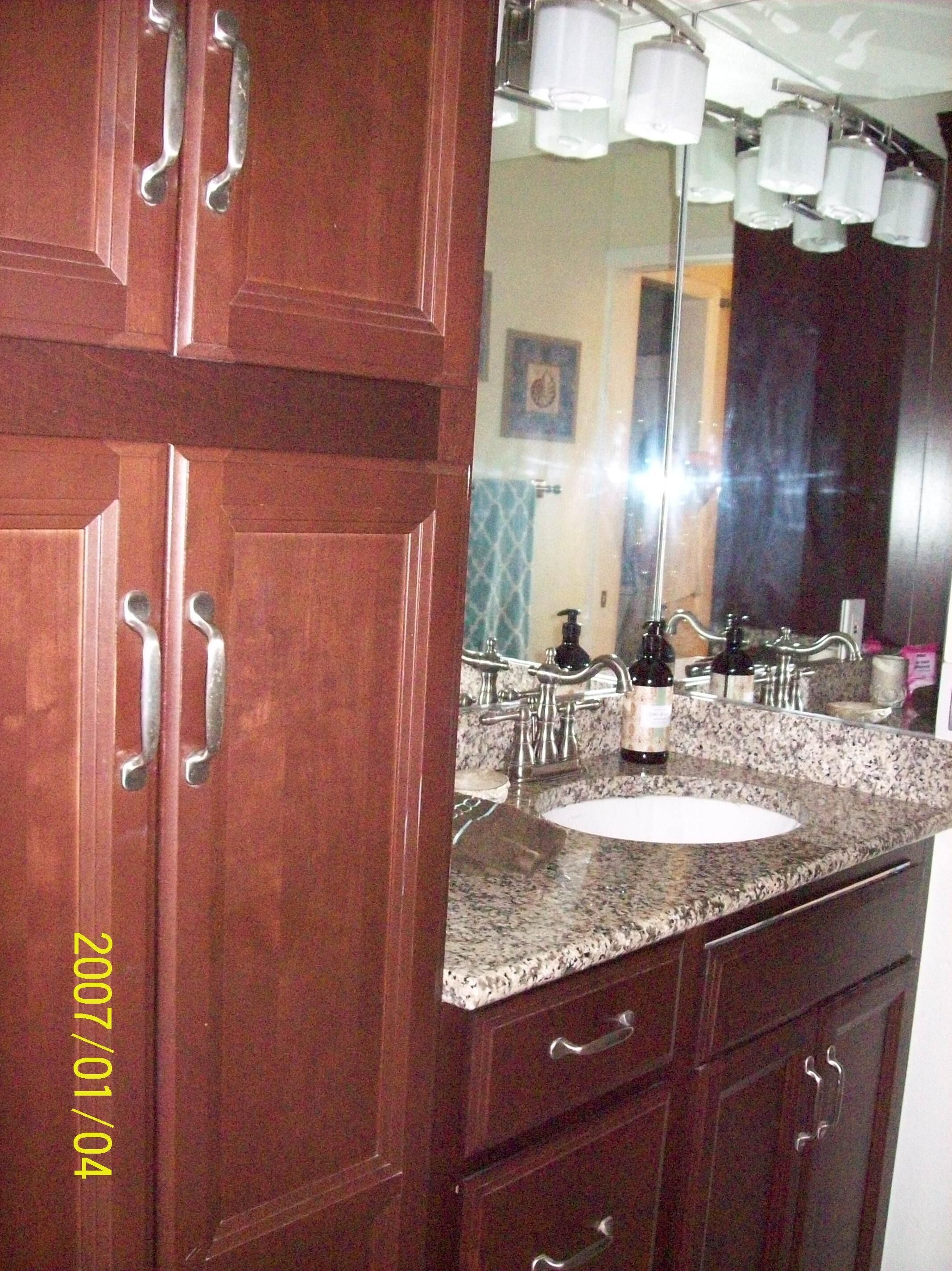 A bathroom with a granite countertop, a sink, and a mirror.