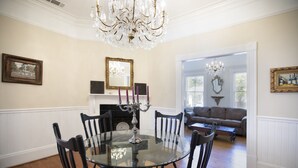 A dining room with a round glass table surrounded by black chairs, a chandelier, and framed pictures on the walls. - Absolutely Awesome, the Captain's Cottage (Savannah)
