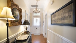 A hallway with a chandelier, framed artwork, and a vintage lamp. - Absolutely Awesome, the Captain's Cottage (Savannah)