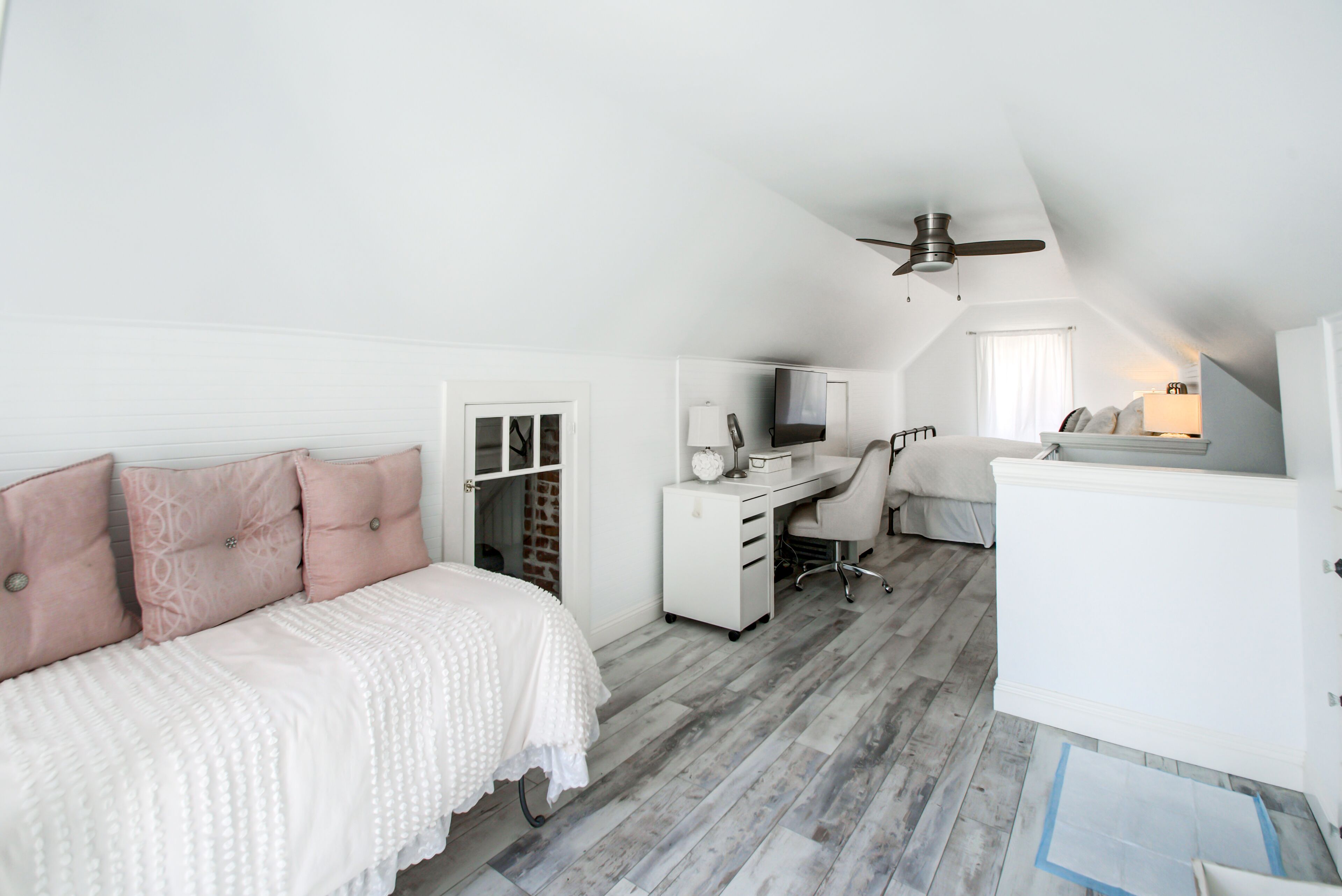 Une chambre à coucher comprenant un lit, un bureau, une chaise et un ventilateur de plafond.