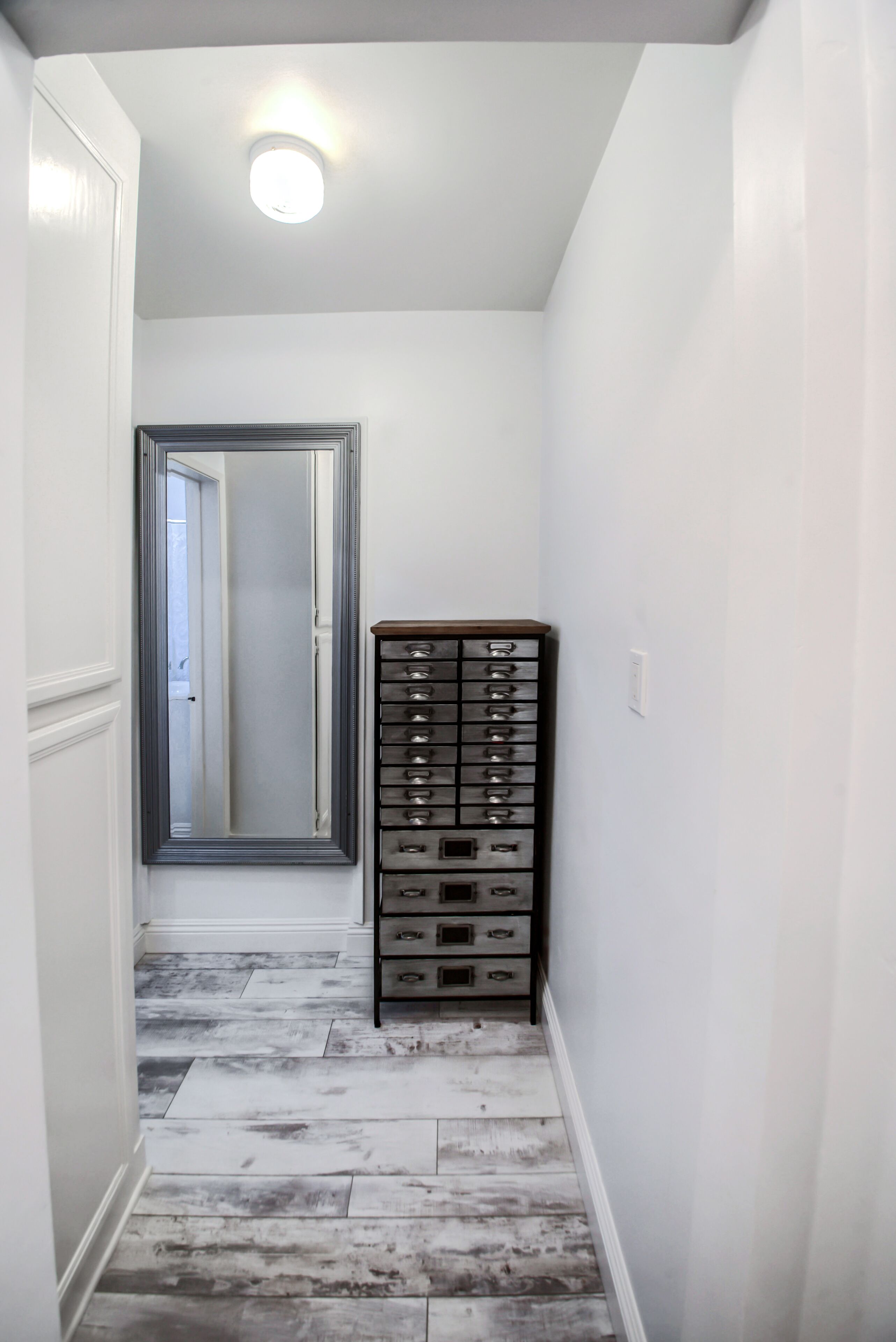 Ein Flur mit einem Spiegelkleiderschrank und einem Metall-Schreibtischschrank.
