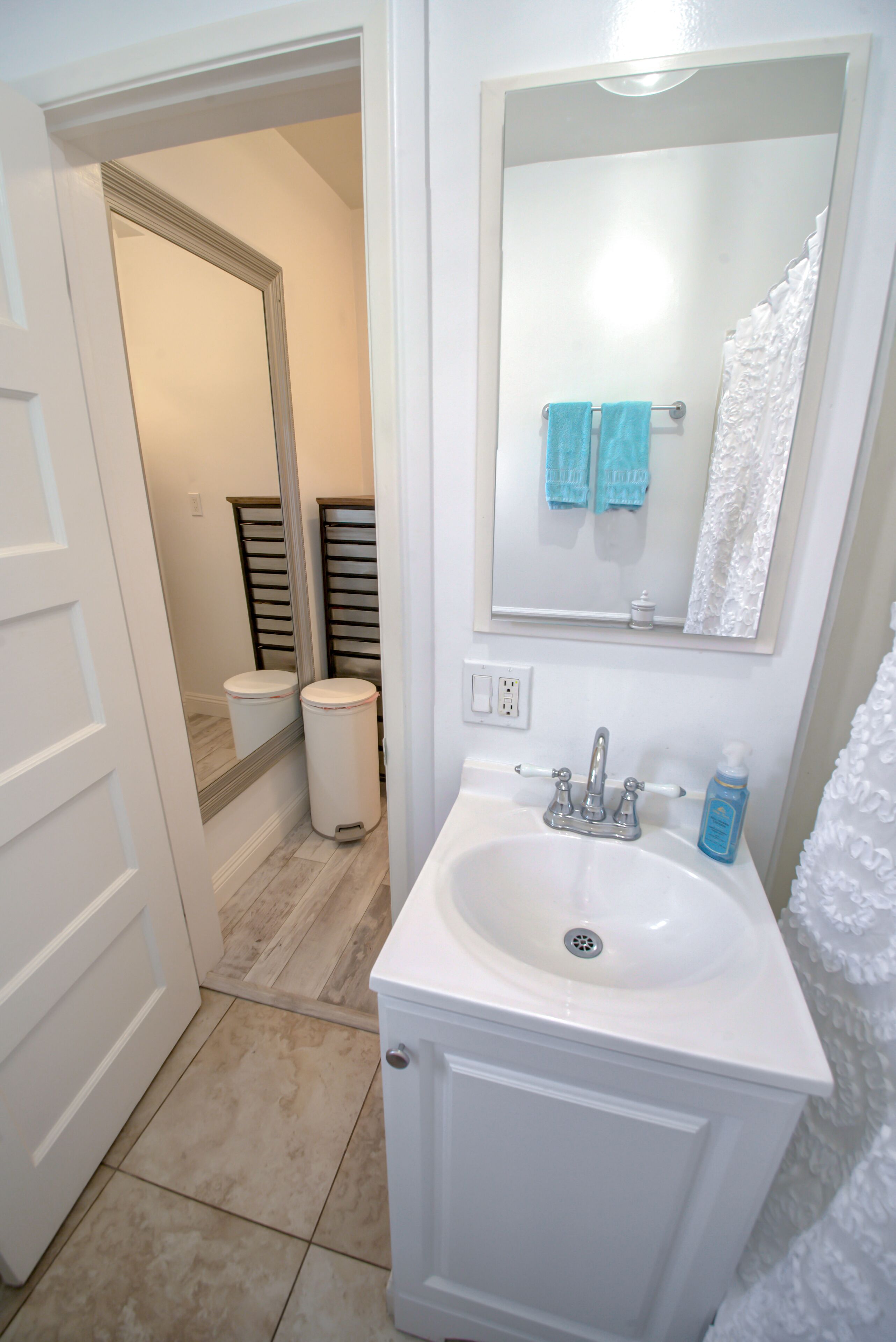 Une salle de bain avec un lavabo blanc, un miroir et un porte-serviettes.