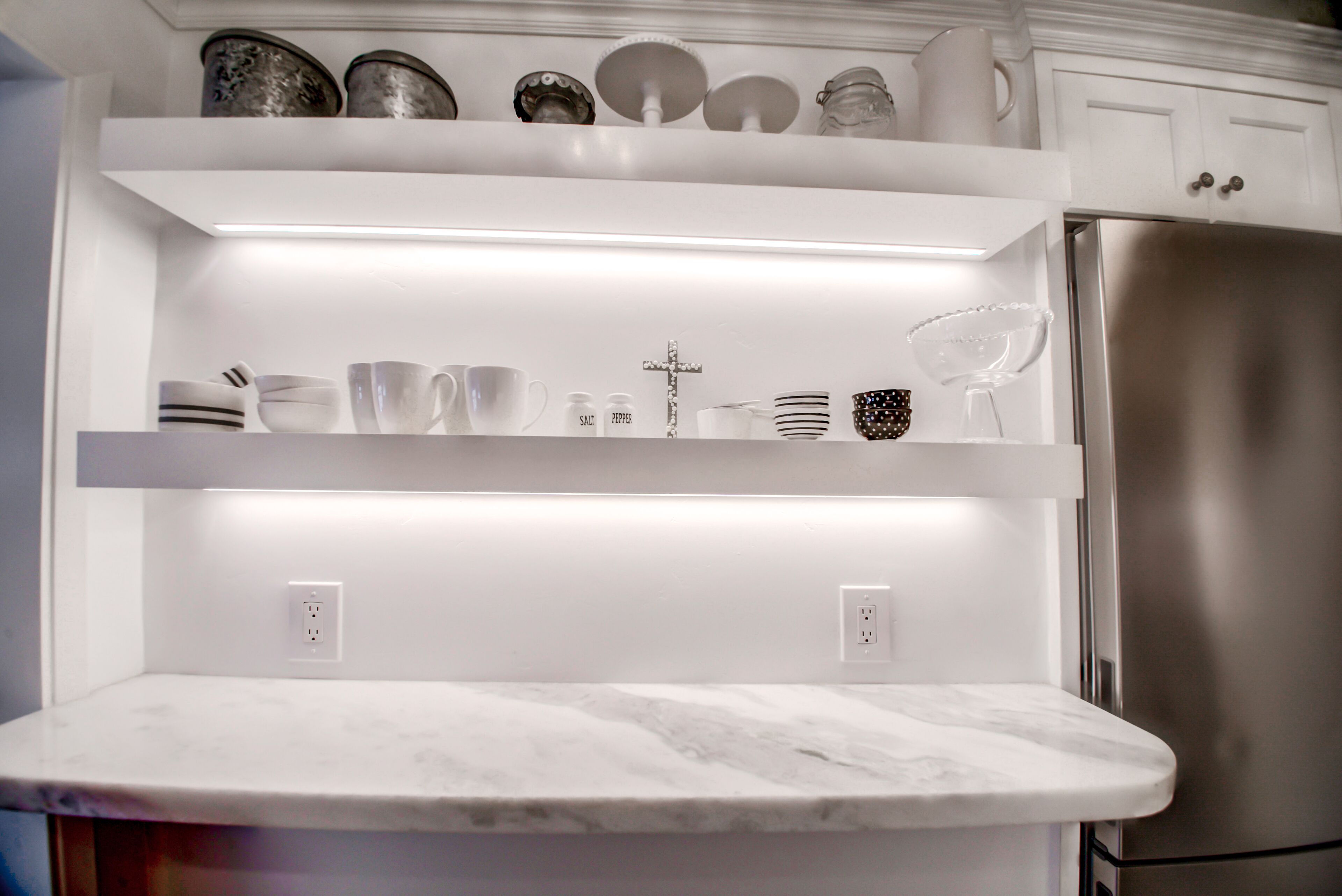A kitchen with white cabinetry, a stainless steel refrigerator, and a marble countertop.