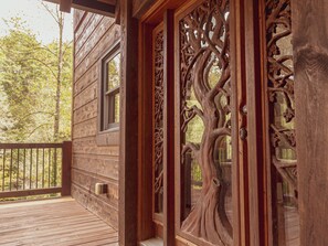 Una cabaña de madera con un porche, ventanas amplias y un adorno tallado en la puerta.