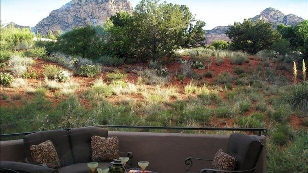 Un espace extérieur aménagé avec une table et des chaises, offrant une vue sur un paysage naturel composé de montagnes et de végétation.