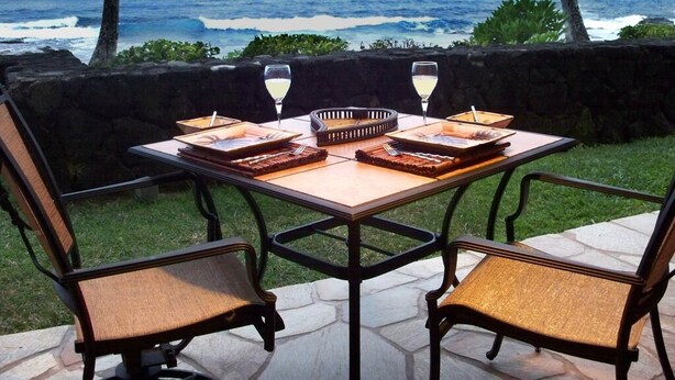 A table set for two with a view of the ocean at sunset. - Quite Simply THE BEST Kona Reef Oceanfront. (Kailua Kona)