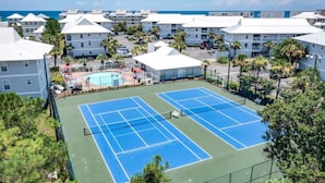A tennis court with a pool, surrounded by white buildings with a view of the ocean. - The best beach views from condo of crystal white sand beach (Seagrove Beach)