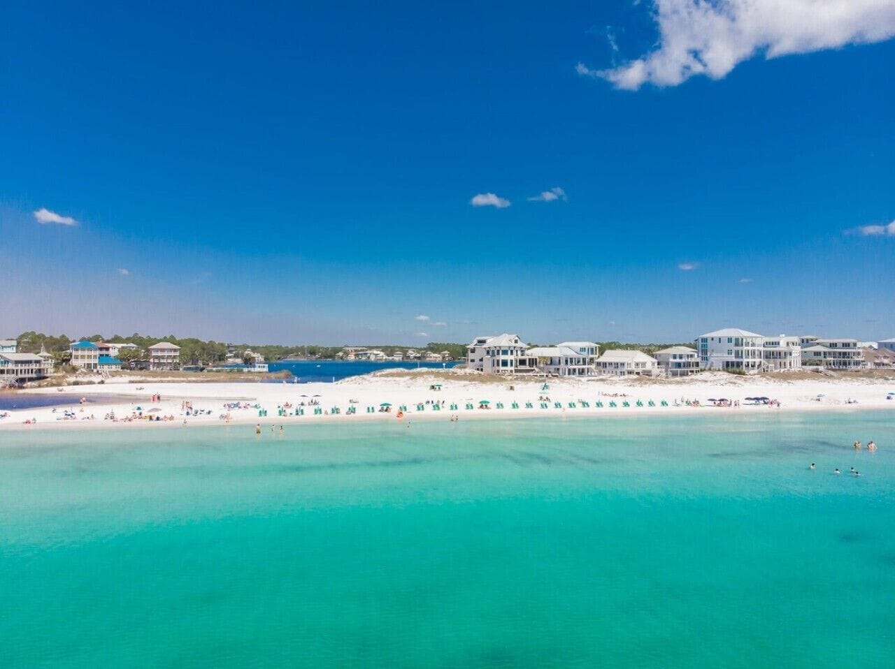 A coastal hotel with multiple buildings, a beach, and clear turquoise waters.
